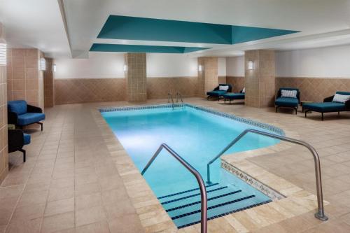 a pool in a hotel room with blue chairs and chairs at The Skirvin Hilton Oklahoma City in Oklahoma City