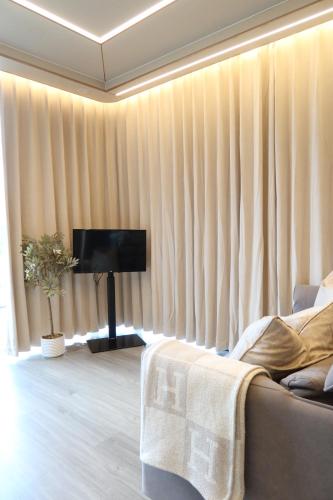 sala de estar con cortinas, sofá y TV en Galactic getaways JUPITER, en Prestatyn