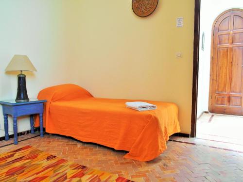 a bed with an orange blanket sitting next to a table at Christina's House in Asilah