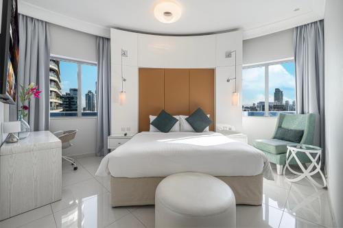 um quarto branco com uma cama grande e uma cadeira em Burj Khalifa view - 2 BR apartment in Downtown em Sabkhah