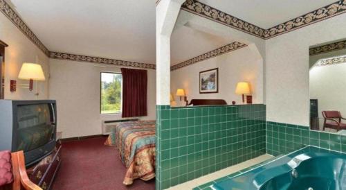 a hotel room with a tub and a bedroom at Quality Inn in Lake Park