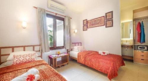 une chambre avec deux lits et une fenêtre dans l'établissement Al-Isha Dharamshala, à Kuta