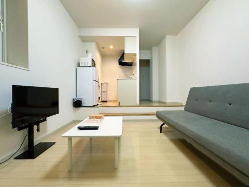a living room with a couch and a tv and a table at 411札幌駅7分と大通駅徒歩6分で好立地な都心を満喫でき綺麗な部屋で快適が生活が実現 in Sapporo