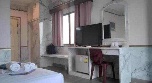 Schlafzimmer mit einem Schreibtisch, einem Spiegel und einem Stuhl in der Unterkunft Phitsanulok Orchid Hotel in Ban Phayom