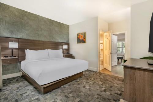 a bedroom with a large white bed and a bathroom at University Park Inn & Suites, an Ascend Collection Hotel in Davis