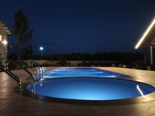 a large blue swimming pool at night at The fox resort in Gundlupet