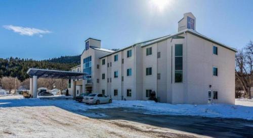 ein großes weißes Gebäude mit einem Auto auf einem Parkplatz in der Unterkunft Econo Lodge Hot Springs South in Hot Springs