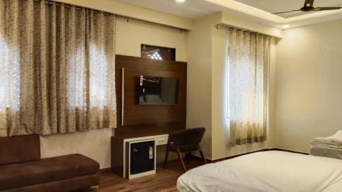 ein Hotelzimmer mit einem Bett und einem Fernseher in der Unterkunft Pink Mahal Hotel & Resort in Jaipur