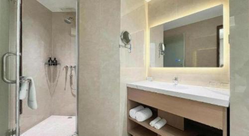 ein Badezimmer mit Waschbecken und Dusche mit Spiegel in der Unterkunft Howard Johnson by Wyndham Sunshine Plaza Ningbo in Ningbo