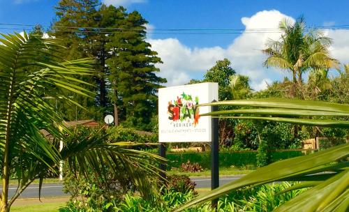 a sign on the side of a road with palm trees at Stay Kerikeri in Kerikeri
