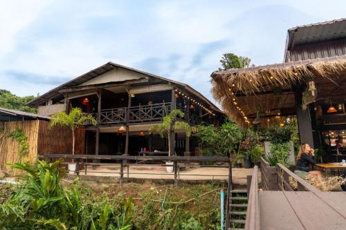 un bâtiment avec un bar et une femme assise devant dans l'établissement Ban Laos Guesthouse, à Vang Vieng