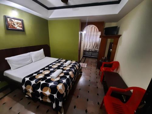 a bedroom with a bed and two red chairs at Hotel caveri comfort in Madikeri