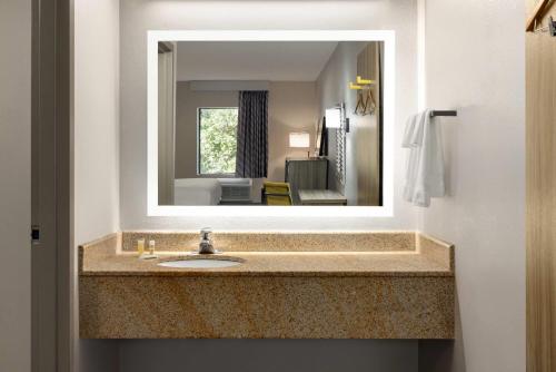 a bathroom with a sink and a mirror at Days Inn by Wyndham Blythewood North Columbia in Blythewood