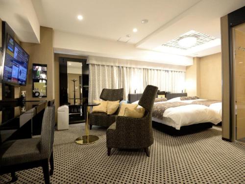 une chambre d'hôtel avec un lit, des chaises et une télévision dans l'établissement APA Hotel Tsukuba Bampaku Kinenkoen Ekimae, à Tsukuba