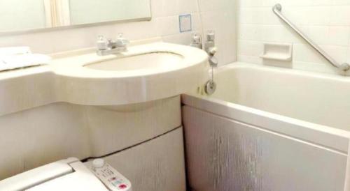 ein Badezimmer mit Waschbecken und Badewanne mit Fernbedienung in der Unterkunft Hotel Ito in Nishi-sakamoto