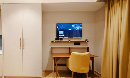 a desk with a yellow chair and a television on a wall at Blue Sapphire Studio Apartment in Ghaziabad