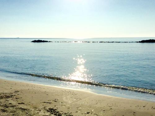 a beach with the sun reflecting on the water at Villa Ro in Porto Columbu - Perdʼe Sali