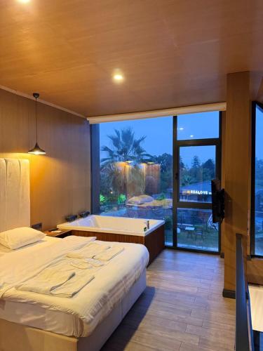 a bedroom with a bed and a tub and a large window at Real Love Villas in Sapanca
