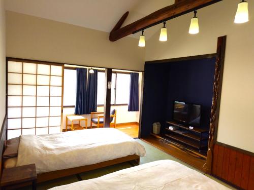 ein Schlafzimmer mit zwei Betten und einem Flachbildfernseher in der Unterkunft 亀井荘 in Ashikita
