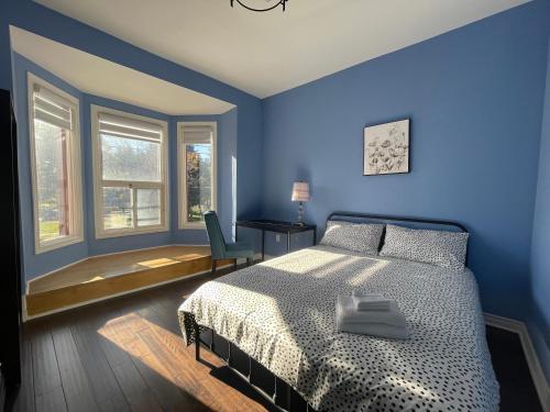 a blue bedroom with a bed and a desk and windows at Quiet King Bedroom near DT Toronto in Toronto