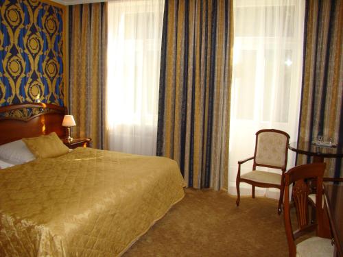 a bedroom with a bed and a chair and a window at Hotel Saint Petersburg in Karlovy Vary
