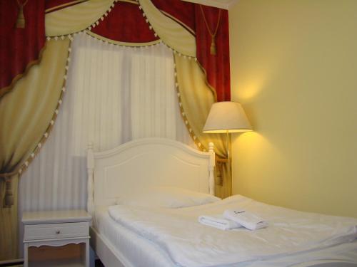 a bedroom with a white bed with a red curtain at Hotel Saint Petersburg in Karlovy Vary