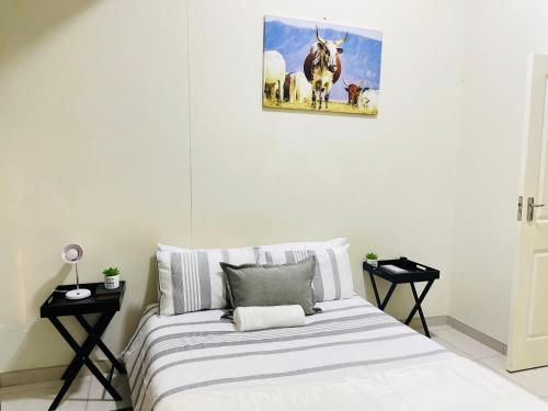 a bed in a white room with a picture of a cow at JB Guest Rooms in Walvis Bay