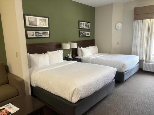 une chambre d'hôtel avec deux lits et une chaise dans l'établissement Sleep Inn & Suites Queensbury - Lake George, à Queensbury