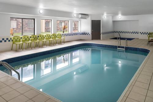 a pool in a hotel room with yellow chairs at Travelodge by Wyndham Fargo in Fargo