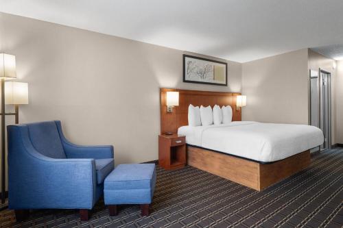 ein Hotelzimmer mit einem Bett und einem blauen Stuhl in der Unterkunft Travelodge by Wyndham Fargo in Fargo
