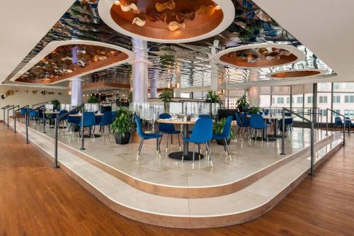a dining room with blue chairs and tables at Fort Pontchartrain Detroit, a Wyndham Hotel in Detroit