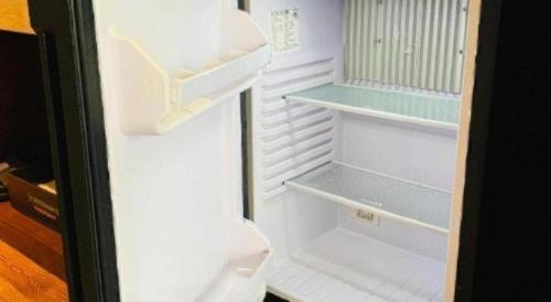an empty refrigerator with its door open in a room at Wyndham Garden Hotel in Lingshui