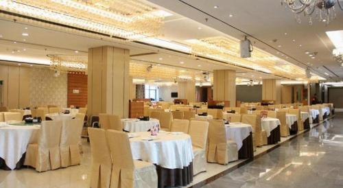 une salle de banquet avec des tables et des chaises blanches dans l'établissement Zhongshan Da Dong Yu Hotel, à Zhongshan