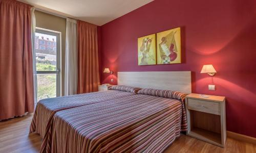 a bedroom with a bed and a red wall at Apartamentos Mar Comillas in Comillas