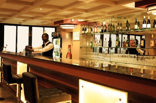 a man standing behind a bar in a restaurant at Lotos Inn & Suites, Nairobi in Nairobi