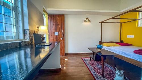 a bedroom with a bed and a desk with a laptop at Arabica Homestay in Somvārpet