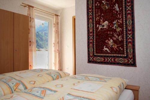 ein Schlafzimmer mit einem Bett und einem Teppich an der Wand in der Unterkunft Ferienwohnung Großvenediger in Virgen