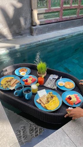 a tray of food on a table next to a swimming pool at Ubud Diary Villa in Ubud