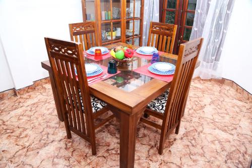 una mesa de madera con 4 sillas y una mesa con fruta. en The Peppermint, en Kandy