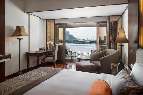 a bedroom with a bed and a living room with a view at Anantara Riverside Bangkok Resort in Bangkok