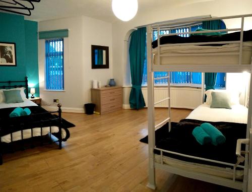 two bunk beds in a room with green walls and wooden floors at Old Trafford Guest House in Manchester