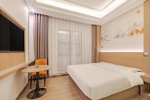 une chambre d'hôtel avec un lit et une table dans l'établissement GreenTree Alliance Anhui Hefei South Passenger Station South High Speed Railway Station Hotel, à Hefei