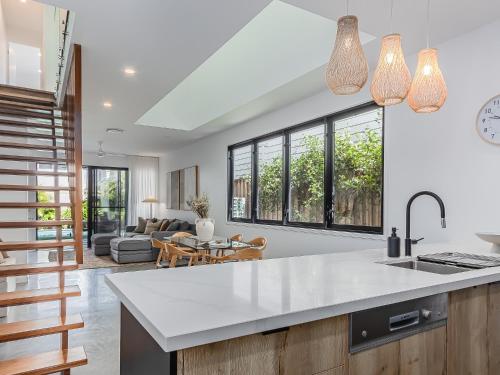an open kitchen and living room with a table and a couch at 3 Bed Beach Retreat with Pool 1 min walk to sand in Kingscliff