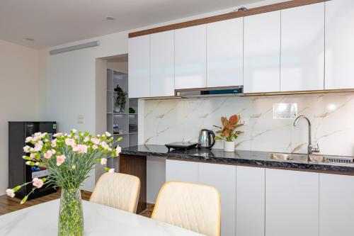 une cuisine avec une table et des fleurs dans un vase dans l'établissement Hera West Lake Apartment, à Hanoï