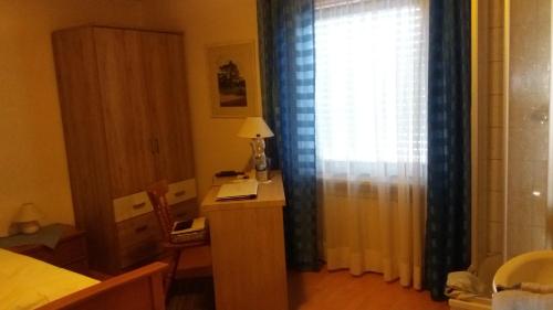 a bedroom with a desk and a window with a window curtain at Landhaus Irma in Bad Füssing