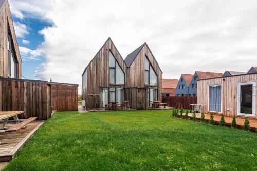 ein mit Holz verkleidetes Haus mit einem grünen Garten in der Unterkunft A&E Houses in Palanga