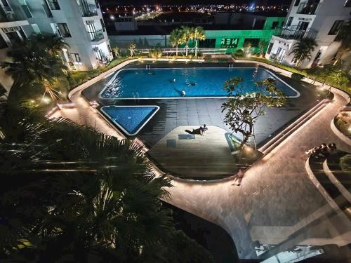 an empty swimming pool at night with trees and buildings at Beer Homestay Nera Garden Hue in Hue