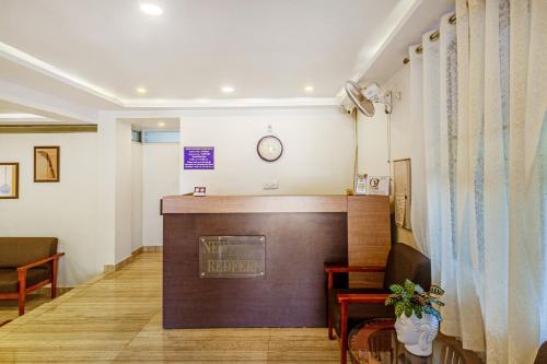 una sala de espera con un atril y un reloj en la pared en Treebo New Redfern, Madikeri, en Madikeri