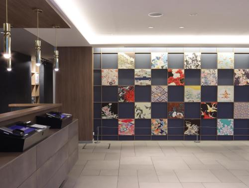a lobby with a tile wall with different types of tiles at Wander Kyoto Nanajo in Kyoto