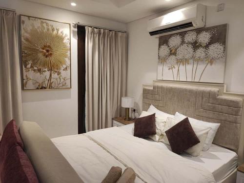 una camera da letto con un letto grande con lenzuola e cuscini bianchi di Hawana Salalah Rosely Studio a Salalah